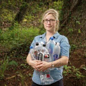 Elizabeth holding up plastic water bottles to inspire awareness of ocean conservation through art 